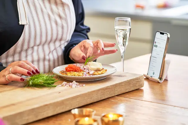 Plating Swedish delicacy with phone showing recipe